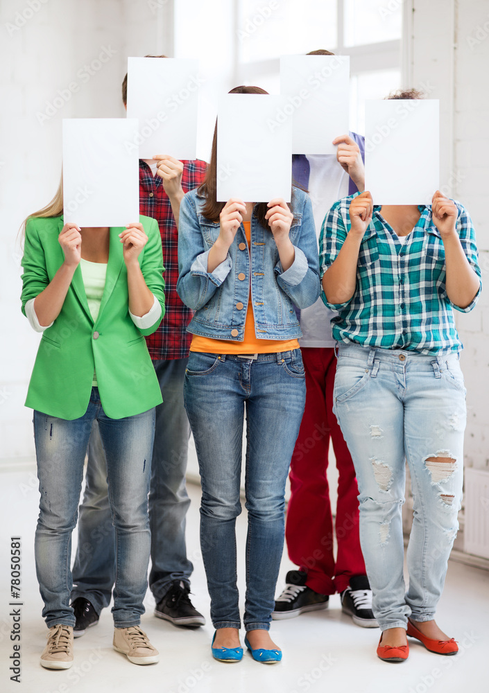 Naklejka premium students covering faces with blank papers
