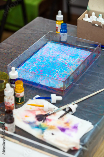 Colorful ebru marbling in special basin with paint and brushes