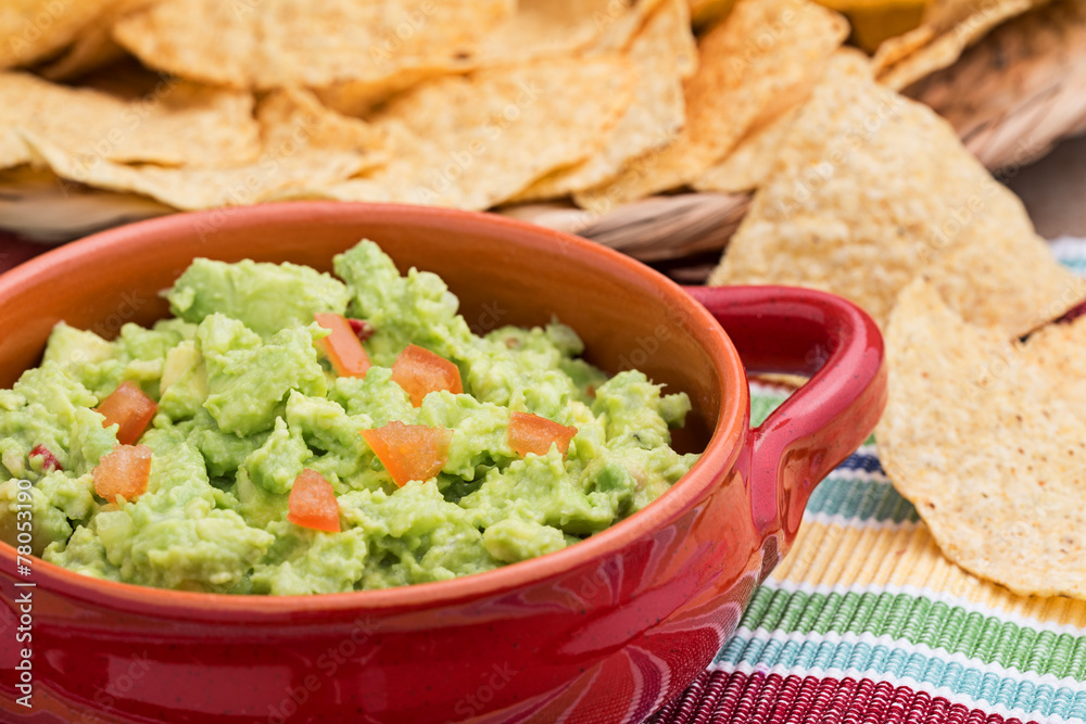 Chunky homemade guacamole in red ceramic dish