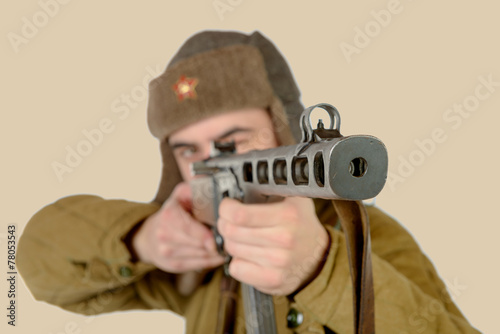 a young Soviet soldier fires with a machine gun