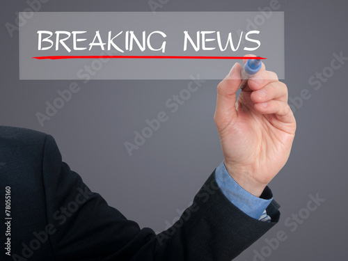 Businessman writing breaking news in the air. Grey background