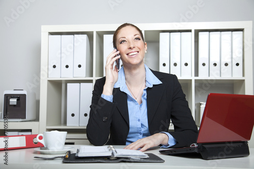 Frau telefoniert am Arbeitsplatz im Büro