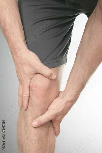 Man with both palm around knee cap to show pain and injury on kn