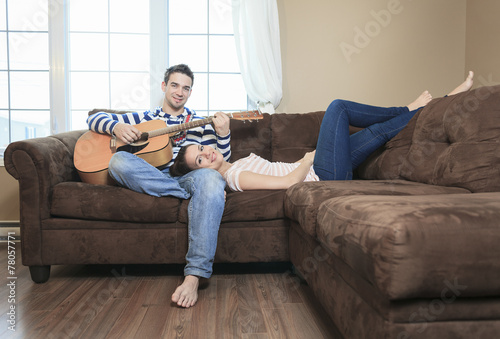 A Handsome man serenading his girlfriend with guitar at home in © Louis-Photo