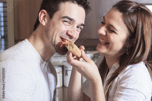 A Happy young couple eating pizza at the kitchen