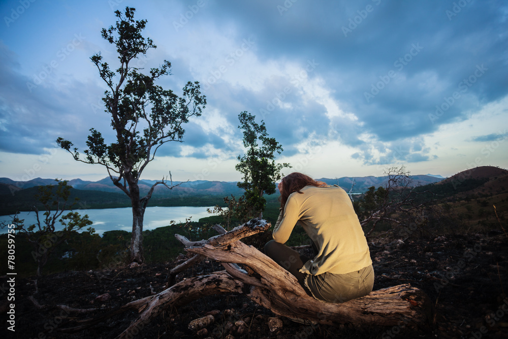 Sad young woman sitting on burned hill