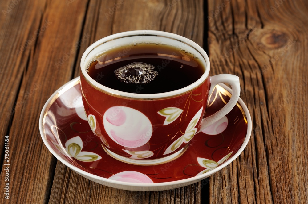 Red cup of black tea with bubbles on wooden background Red cup of black tea with bubbles on wooden background