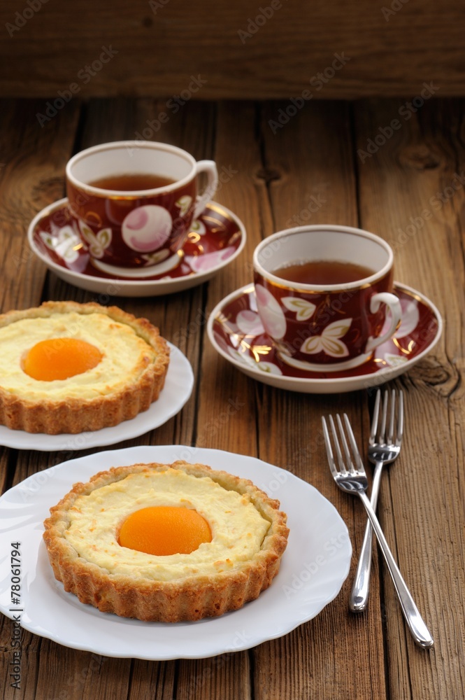Peach tarts and cups of black tea on wooden background Peach tarts and cups of black tea on wooden background
