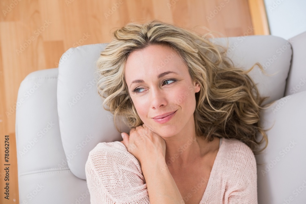 Smiling blonde lying on couch thinking Smiling blonde lying on couch thinking