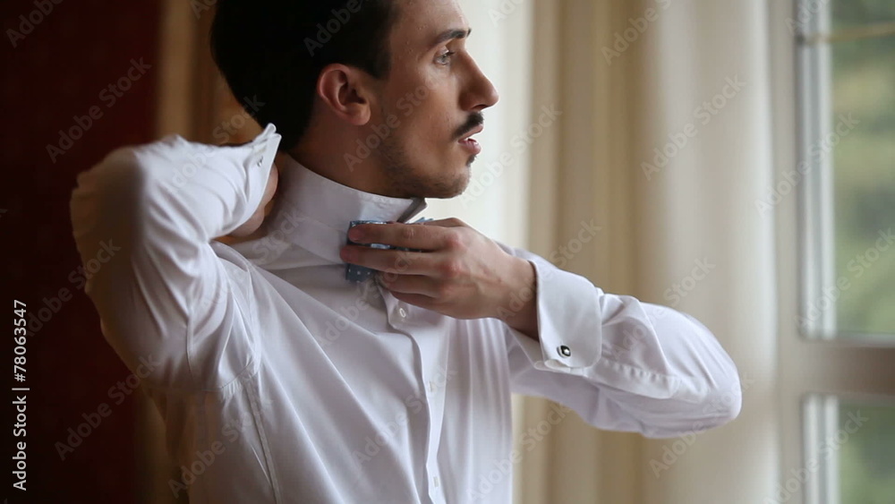 A man by the window wears bow tie A man by the window wears bow tie
