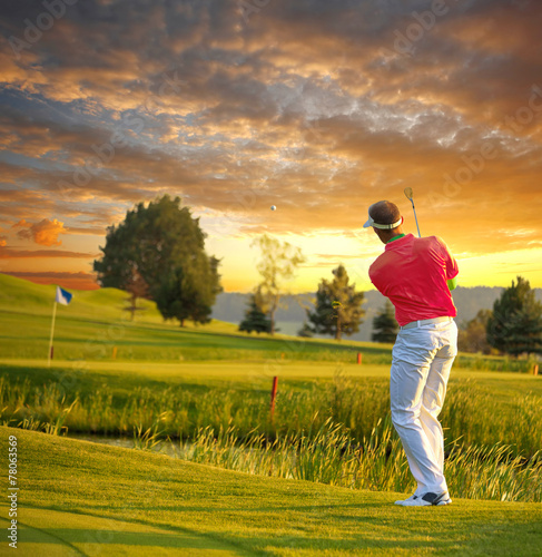Man playing golf against colorful sunset
