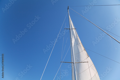 Mast and sail of yacht on blue sky background