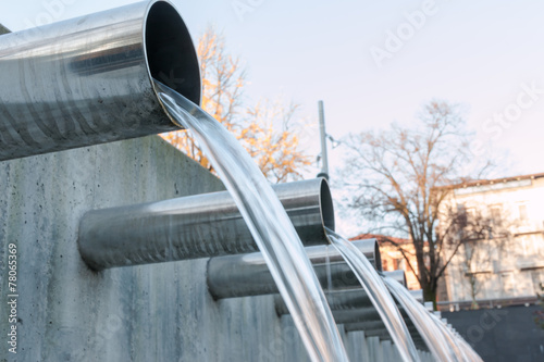 Fotografering Water flowing out from steel pipes