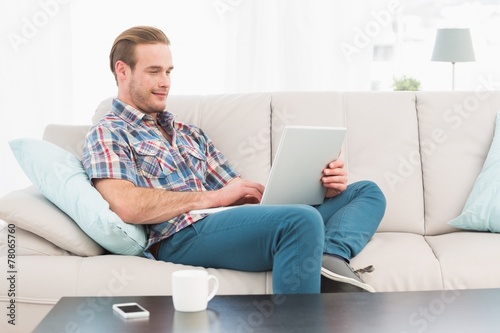 Relaxed man sitting on sofa using laptop
