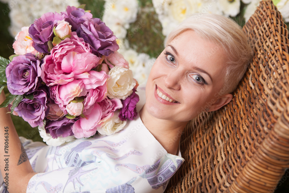 blond woman holding flowers, looking up, short haircut - obrazy, fototapety, plakaty 