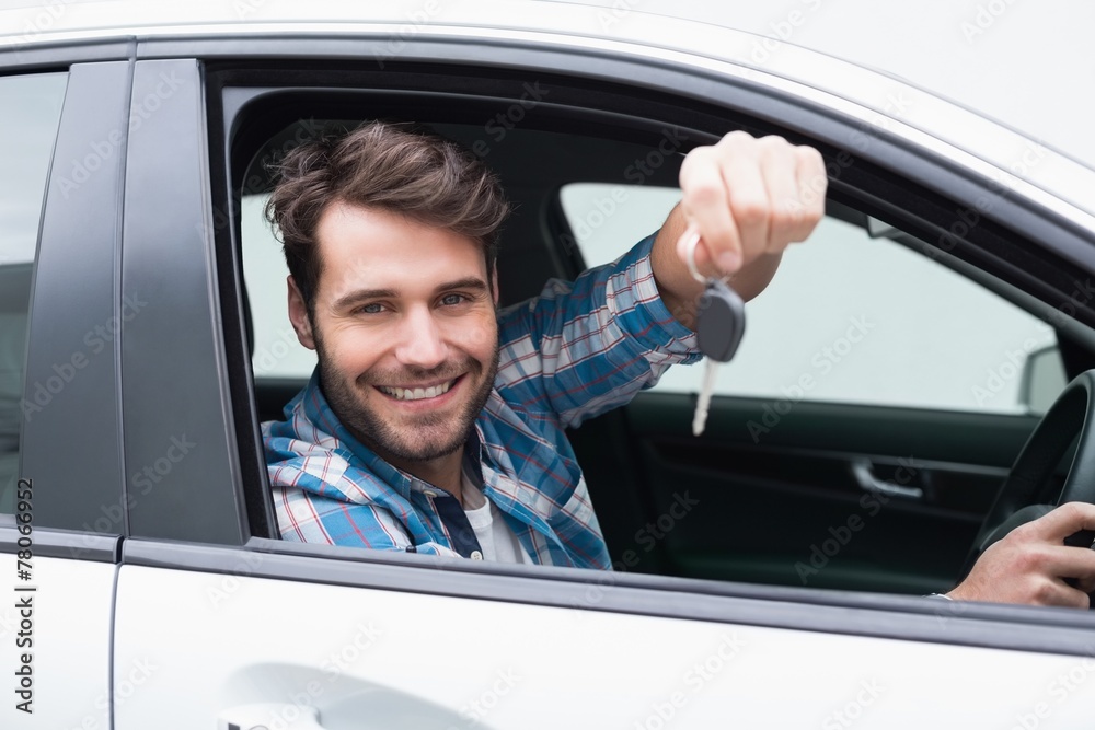 Young man smiling at camera showing key Young man smiling at camera showing key