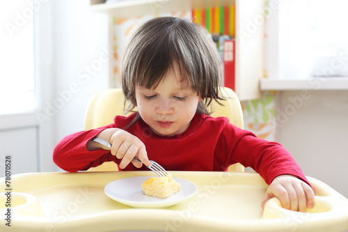 2 years boy in red shirt eating omelette