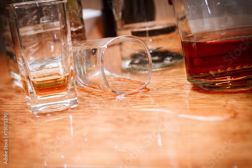 Canvas Print Glass, spilled whiskey and empty bottles on the bar.Alcoholism c