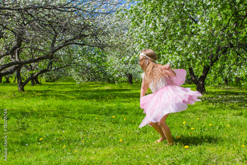 Adorable little girl have fun in blossoming apple tree garden Adorable little girl have fun in blossoming apple tree garden