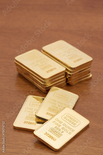 One ounce gold bars on dark wood surface