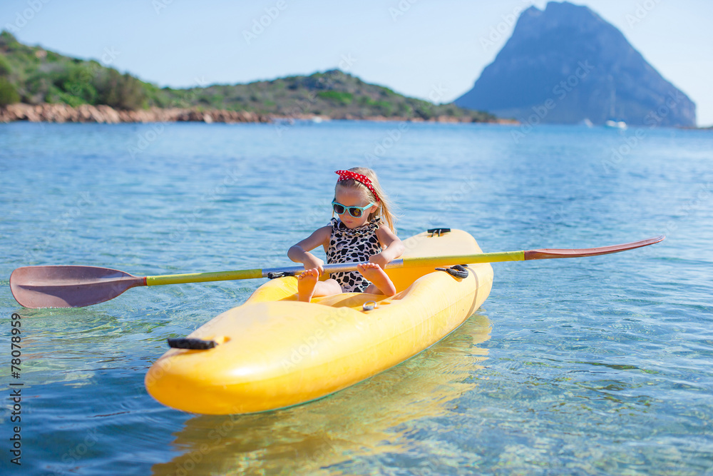 Little adorable happy girl kayaking in blue sea during summer