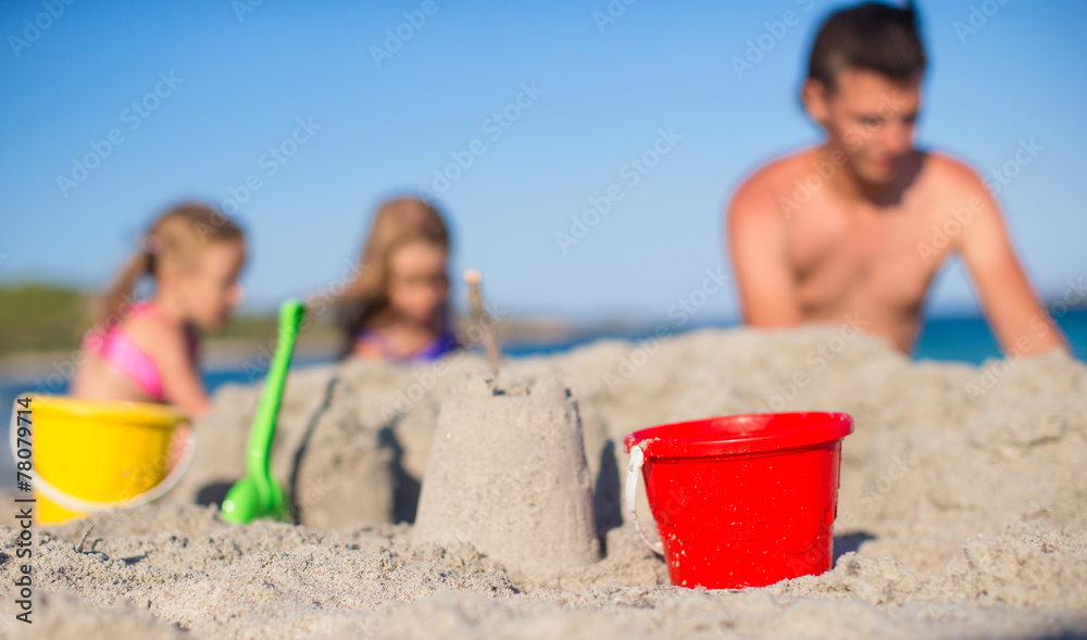 Father and adorable little daughter playing with beach toys