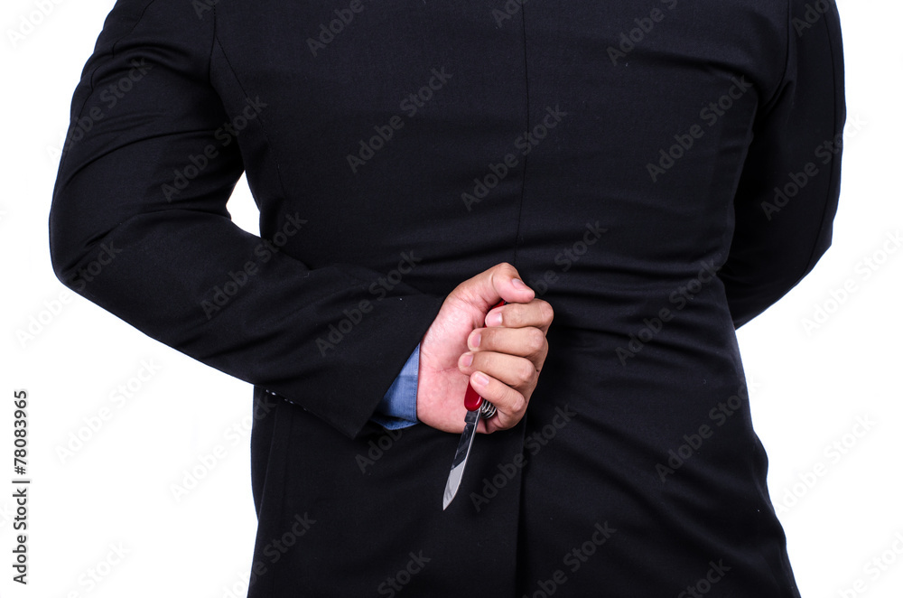 Businessman holding pocket knife behind his back., business conc