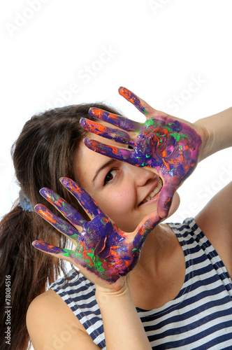Woman looks out her hands painted in colorful paint