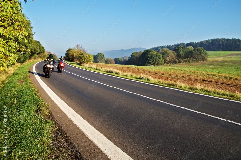 Country landscape with an asphalt road. Two motorcycles.