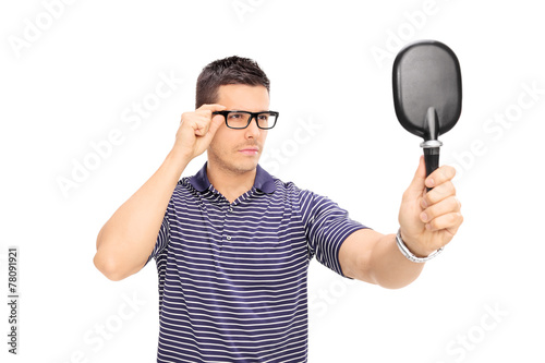 Man with glasses looking himself in a mirror