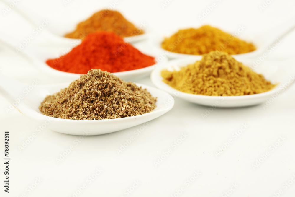 Different kinds of spices in ceramics spoons isolated on white Different kinds of spices in ceramics spoons isolated on white