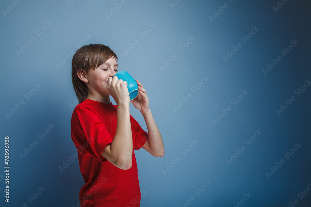 European-looking boy of ten years holding a mug on a gray back European-looking boy of ten years holding a mug on a gray back