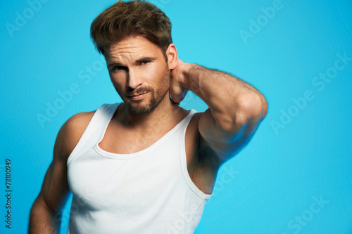 Good looking man in white undershirt against blue background