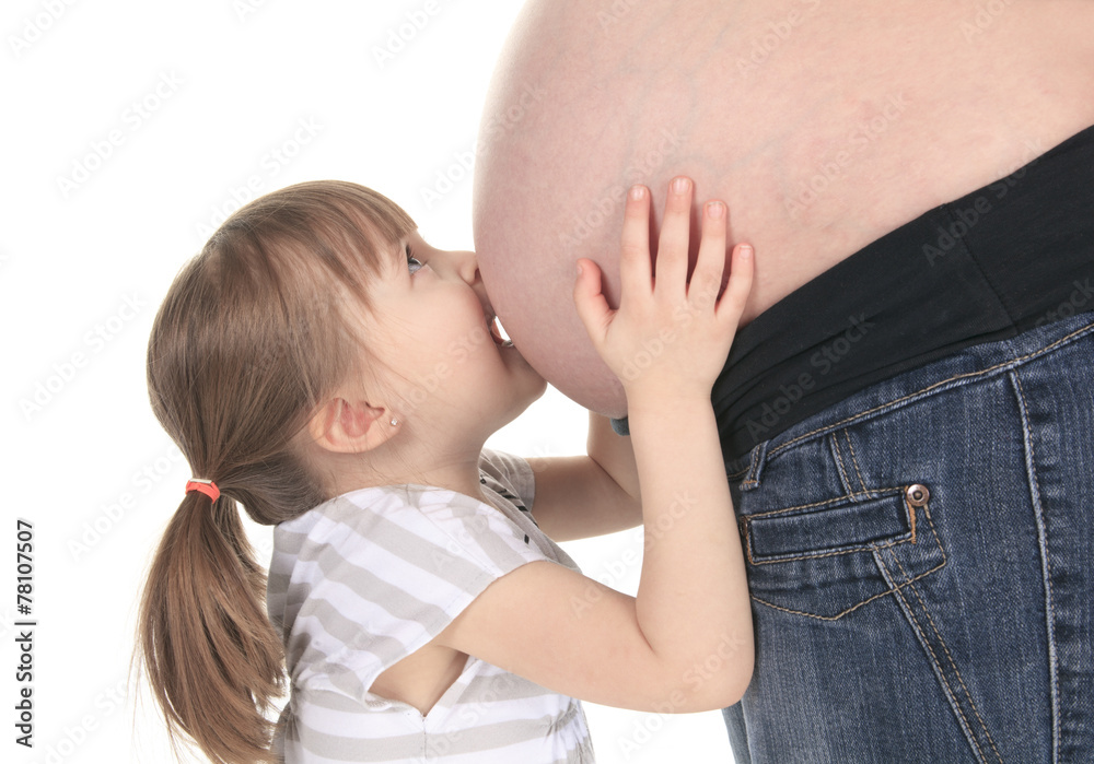 Little girl kissing her mothers baby bump on white background Little girl kissing her mothers baby bump on white background