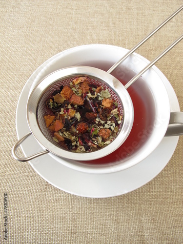 Foto Kräutertee mit Früchten und Blüten im Teesieb