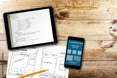 website wireframe sketch and programming code on digital tablet