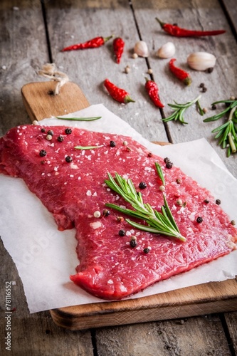 raw meat steak on a cutting board with rosemary