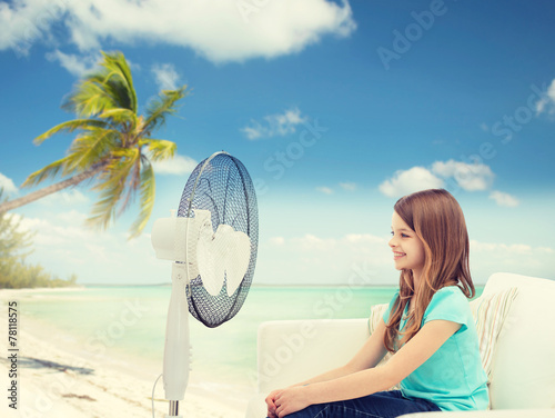 smiling little girl with big fan at home