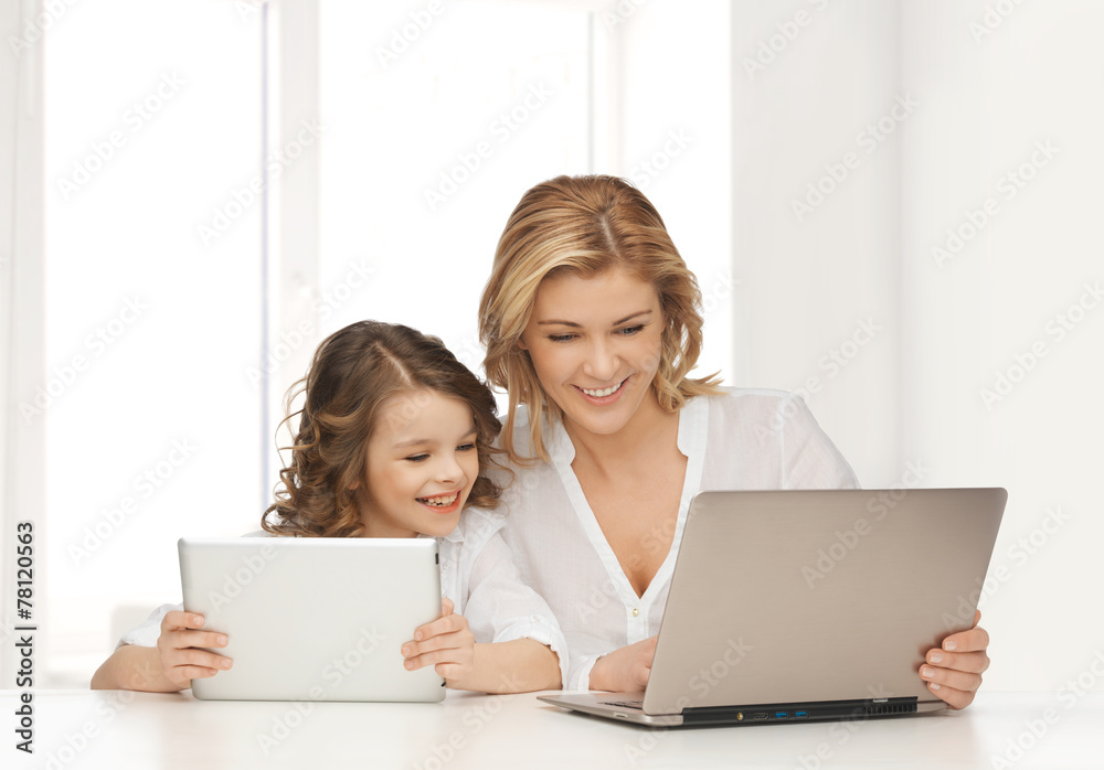 mother with girl looking to laptop and tablet pc mother with girl looking to laptop and tablet pc