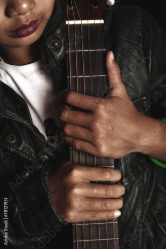 Girl rocker in leather jacket holding a guitar in his hands