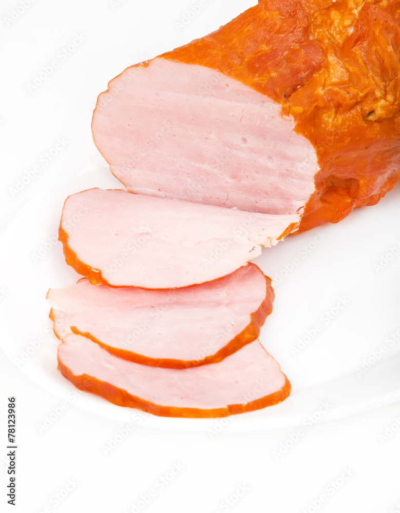 Large piece of ham with cut slices on plate, isolated on white b