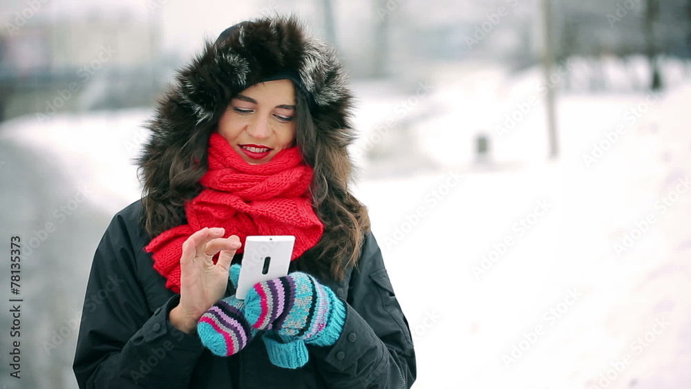Woman texting on smartphone and smiling to the camera in the sno
