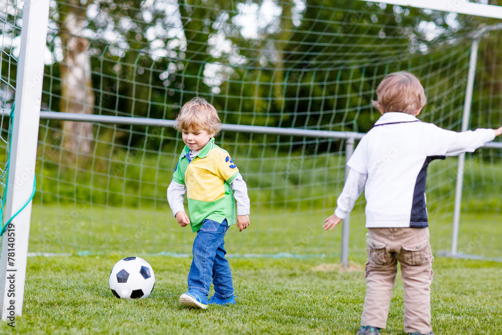 Two little sibling boys playing soccer and football Two little sibling boys playing soccer and football