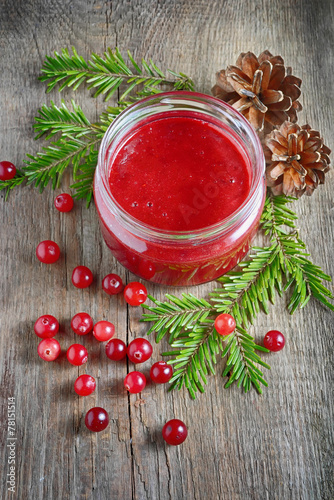 Cranberry jam in jar on wooden background