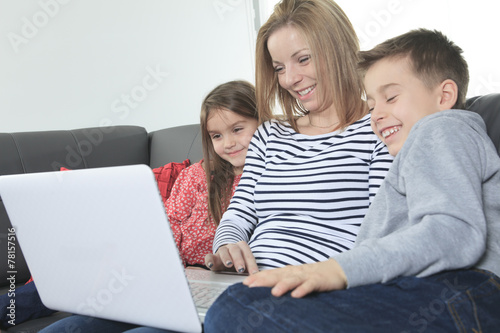 Image of friendly family sitting on the sofa and looking at lapt