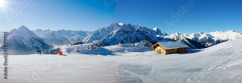 Plakat Zimowa panorama z narciarzami i chatą narciarską