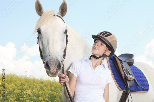 A white horse on yellow flower field with a rider. © Louis-Photo