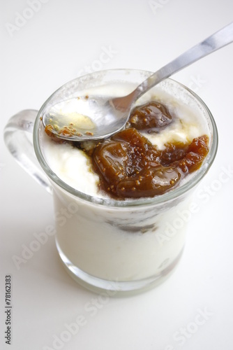 Cup of yogurt with spoon and figs