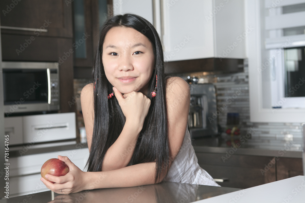 Portrait of smiling teenager girl with apple in kitchen Portrait of smiling teenager girl with apple in kitchen