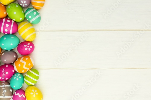Colorful Easter egg side border against white wood